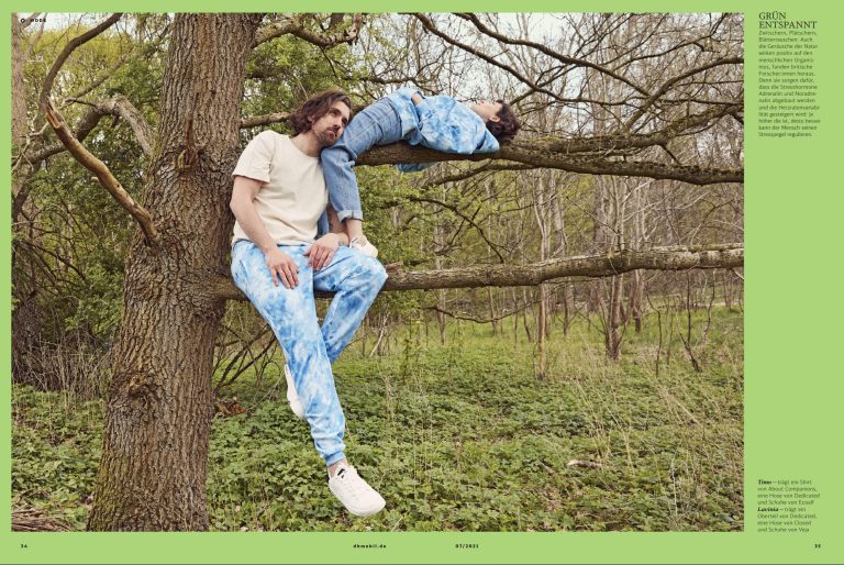 Magazindoppelseite: Mann und Frau liegen entspannt auf einem Baumast im Wald