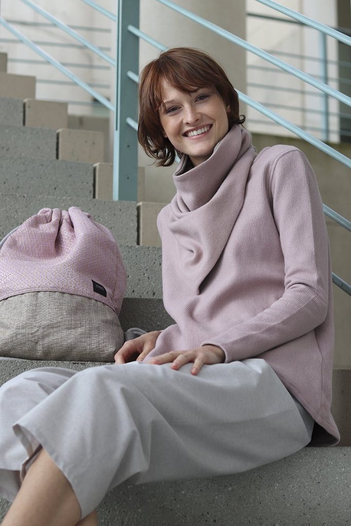 Frau im rosa Langarmshirt mit Rucksack auf einer Treppe