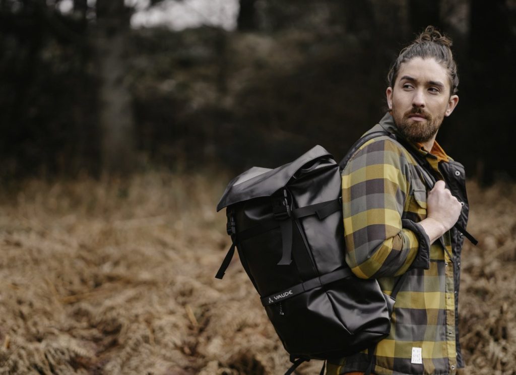 Mann mit schwarzem VAUDE-Rucksack in herbstlicher Landschaft